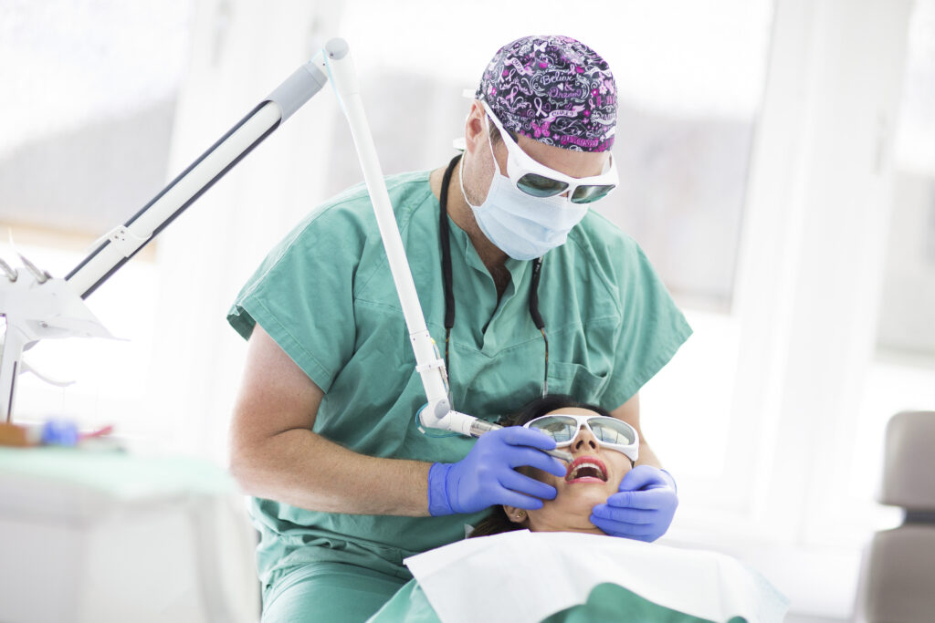 Tandläkare utför tandbehandling med laser.
